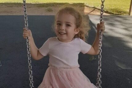 Nevaeh Austin on a swing in a park.