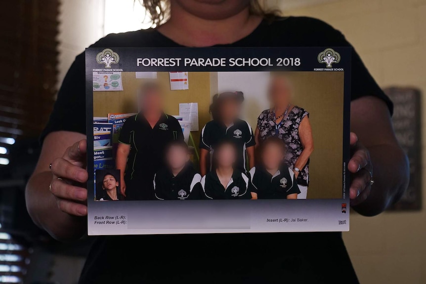 A woman holding a classroom photo in which a student has been digitally inserted.