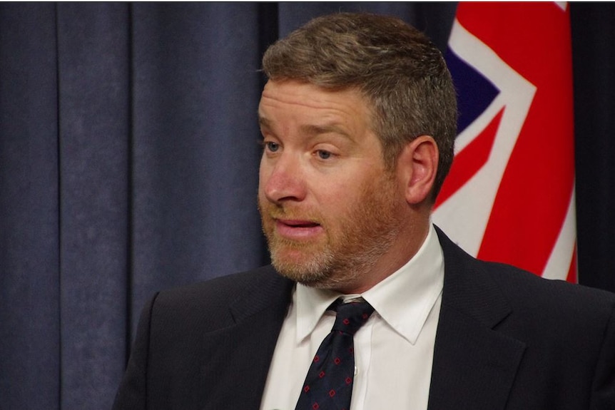 Close-up of WA Nationals Leader Brendon Grylls in front of flag.