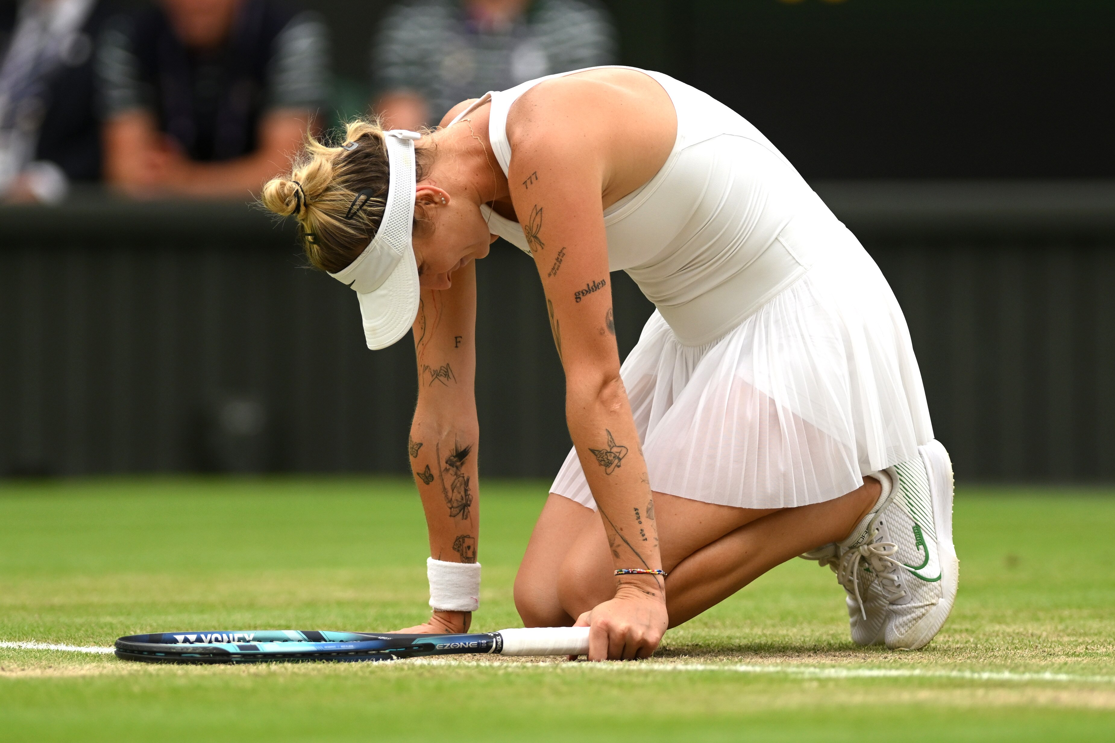 Marketa Vondrousova sinks to her knees on Wimbledon's Centre Court.