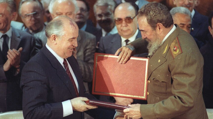 Soviet Leader Mikhail Gorbachev and Cuban President Fidel Castro exchange a red folder.