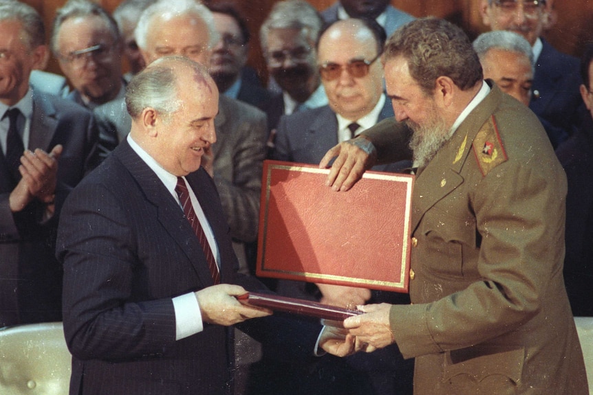 Soviet Leader Mikhail Gorbachev and Cuban President Fidel Castro exchange a red folder.