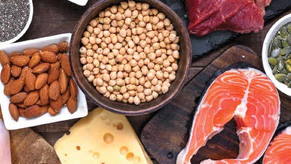 A variety of foods including cheese, almonds, fish and chickpeas spread out on a table.