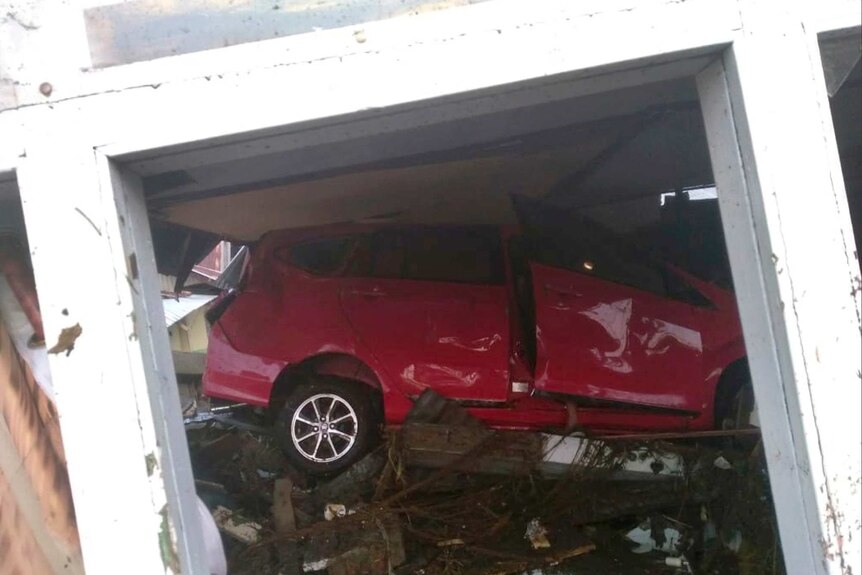 Car stuck under building after tsunami in Palu