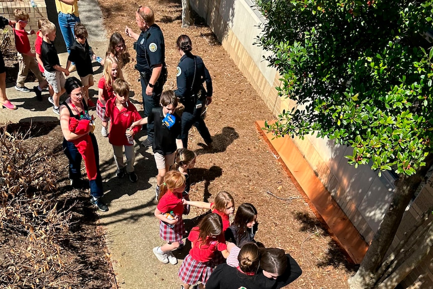 Children hold hands as they exit the school.