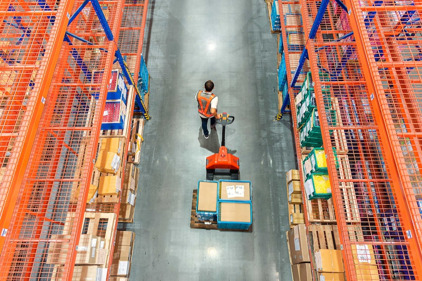High angle view of a male pulling a trolley in a warehouse.