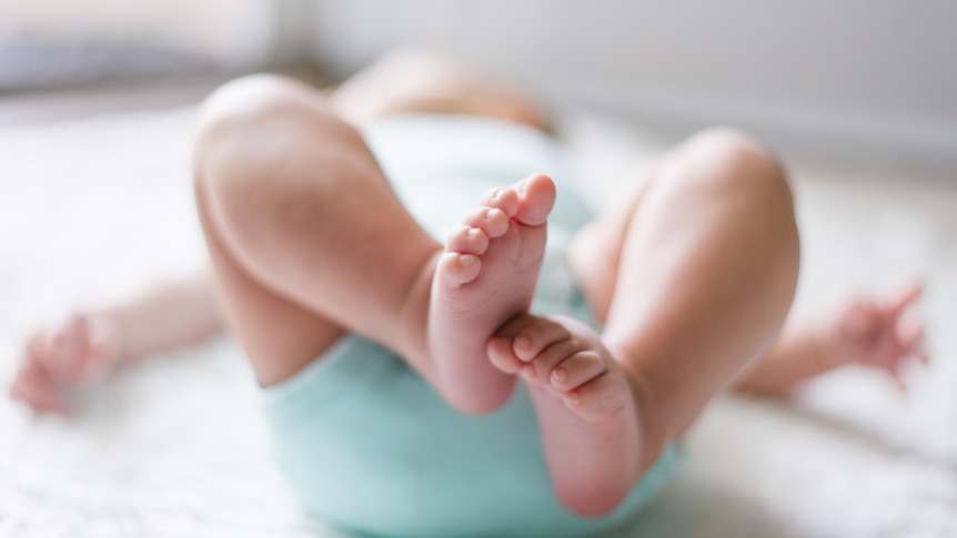 A baby lays down on its back and a photo is taken of its feet.