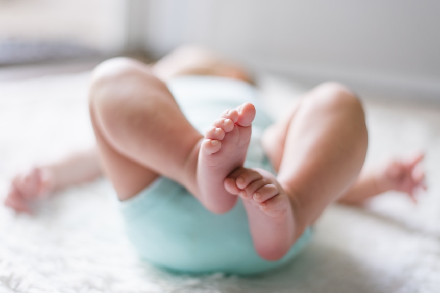 A baby lays down on its back and a photo is taken of its feet.