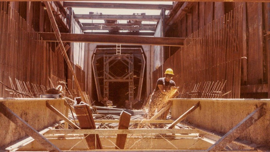 A man works on a steel structure outside a tunnel entrance