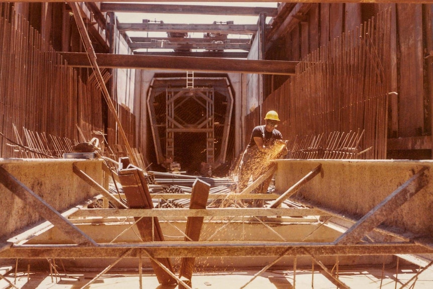 A man works on a steel structure outside a tunnel entrance