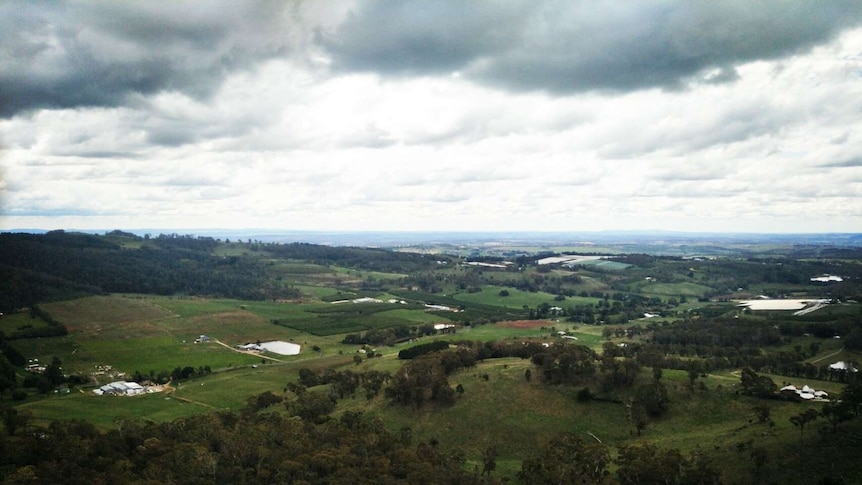 An aerial photo of grey clouds and green paddocks.