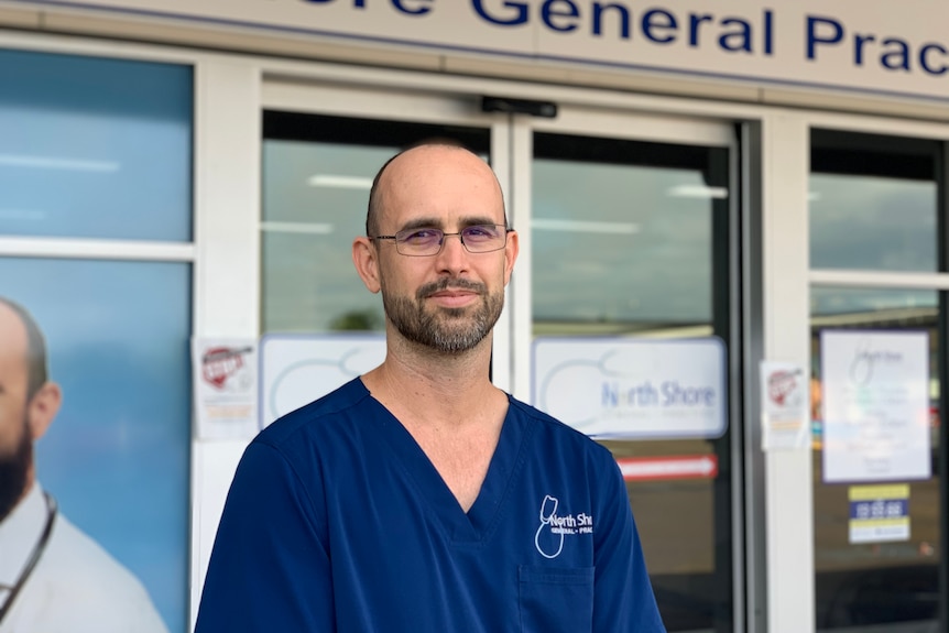 GP stands in navy blue scrubs outside building