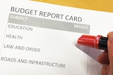 Budget report card with pen hovering overhead.