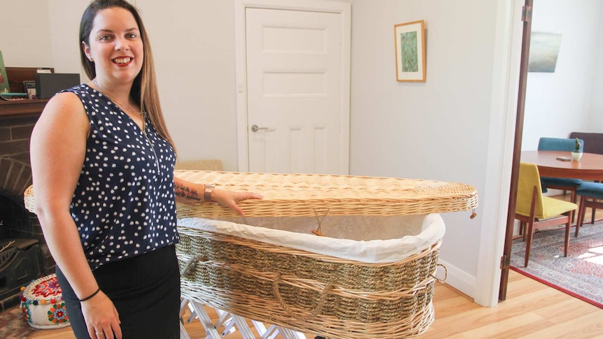 Woman stands with willow casket