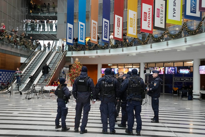 Les policiers sont rassemblés dans une grande salle, des banderoles de différentes couleurs arborent les marques de TVP.