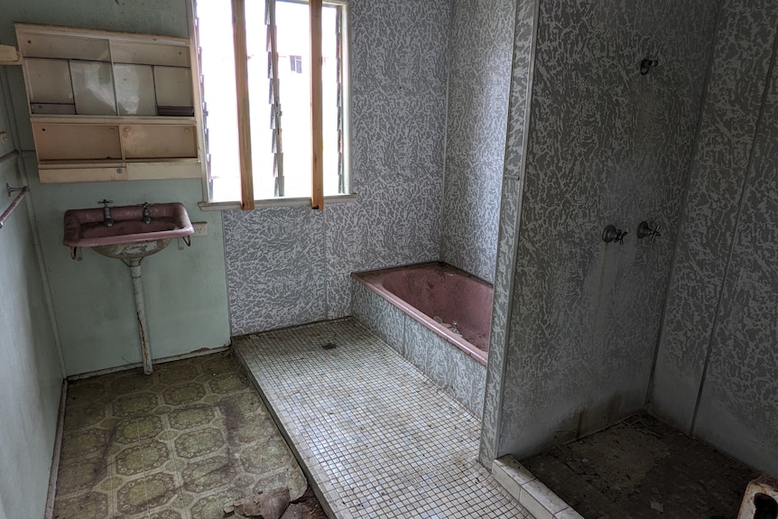 A old bathroom with dirty floors and walls and ripped up tiling