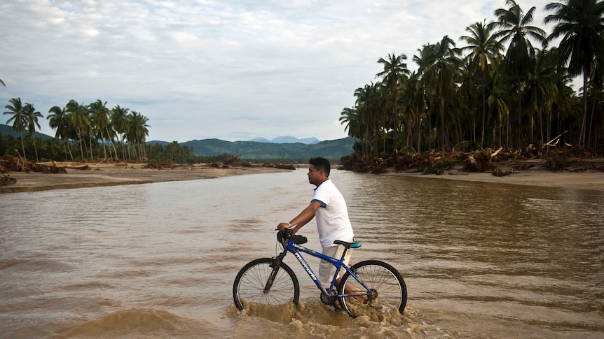 A man wades through the water as he crosses a river in Coyuca de Benitez, state of Guerrero, on September 21, 2013 as Mexico struggles to recover from the effects of heavy rain that drenched two-thirds of the country over the last week, killing more than 100 people in landslides and flooding