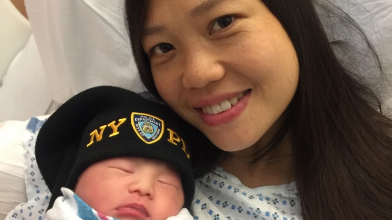 Pei Xia Chen in hospital with her newborn daughter, who is wearing an NYPD hat.