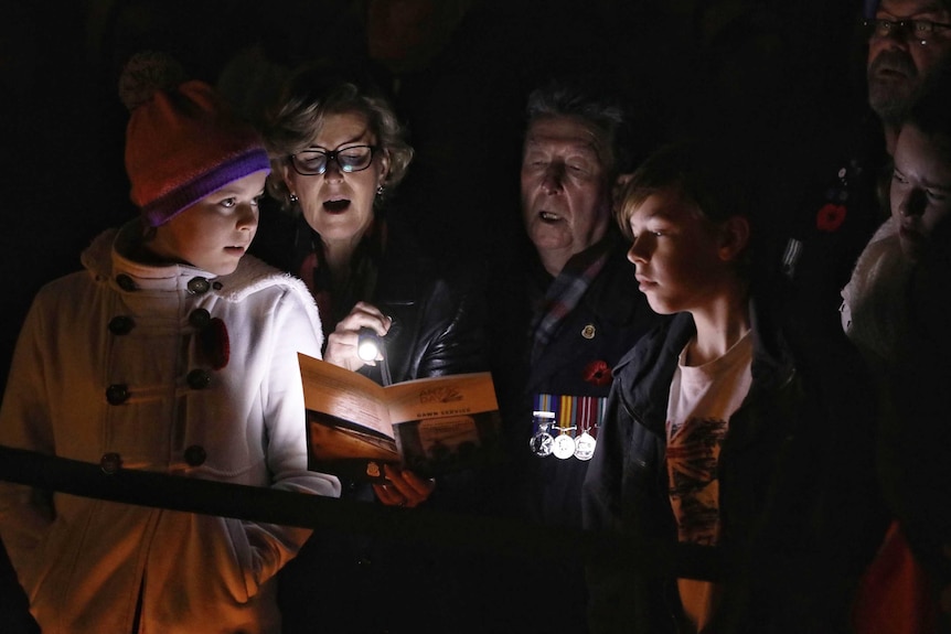 A family looks at the proceedings program and sings.