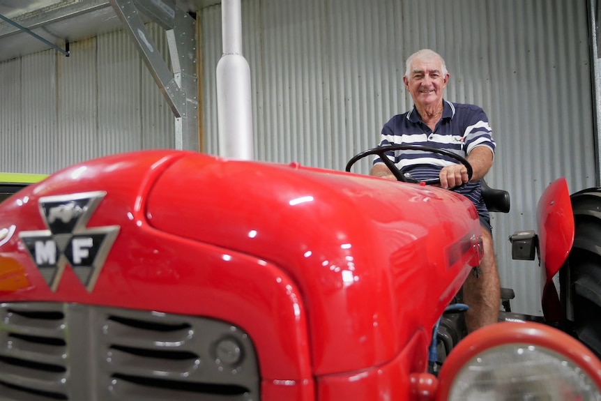Photo of a grey-haired man sitting in red tractor.