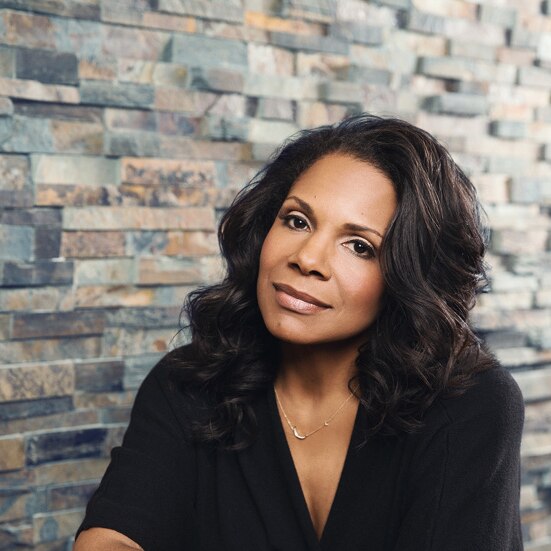 Audra McDonald sits against a tiled wall, looking serenely at the camera