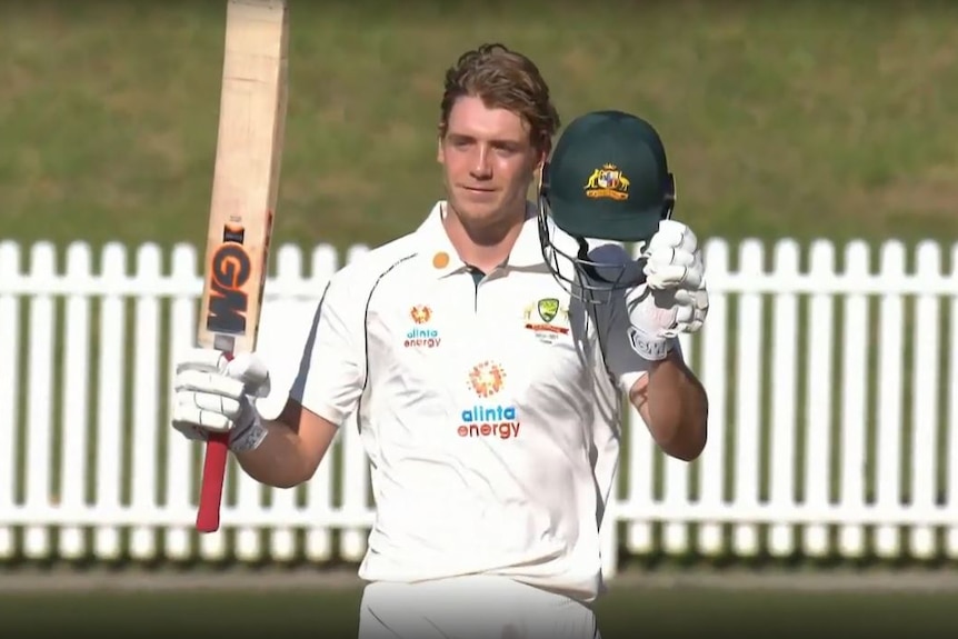 With a wry smile, Cameron Green holds his bat and helmet up in recognition of applause