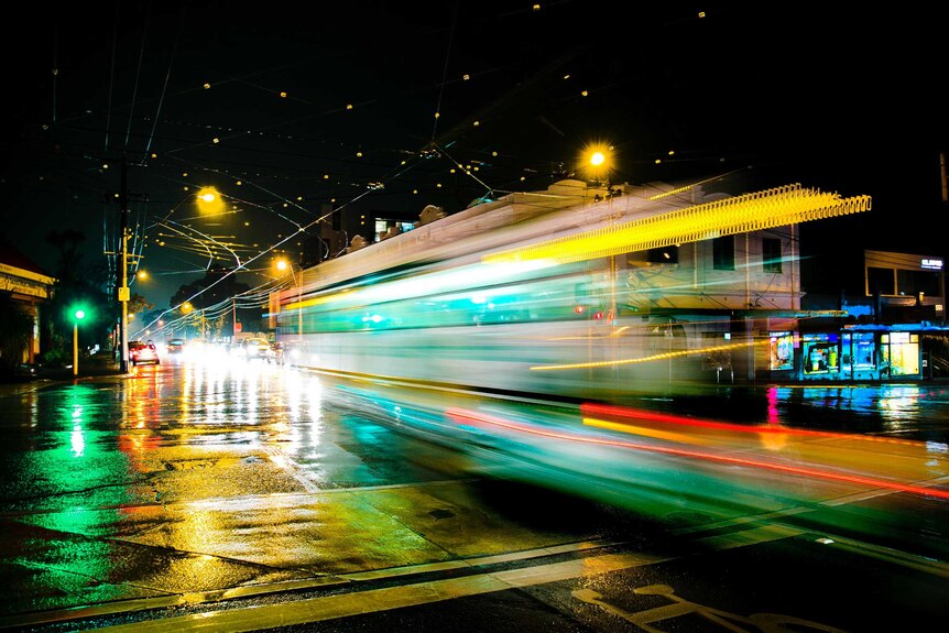 A tram moves through an intersection in Hawthorn on a rainy night.