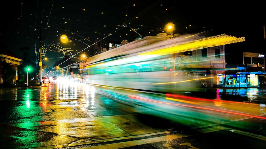 A tram moves through an intersection in Hawthorn on a rainy night.