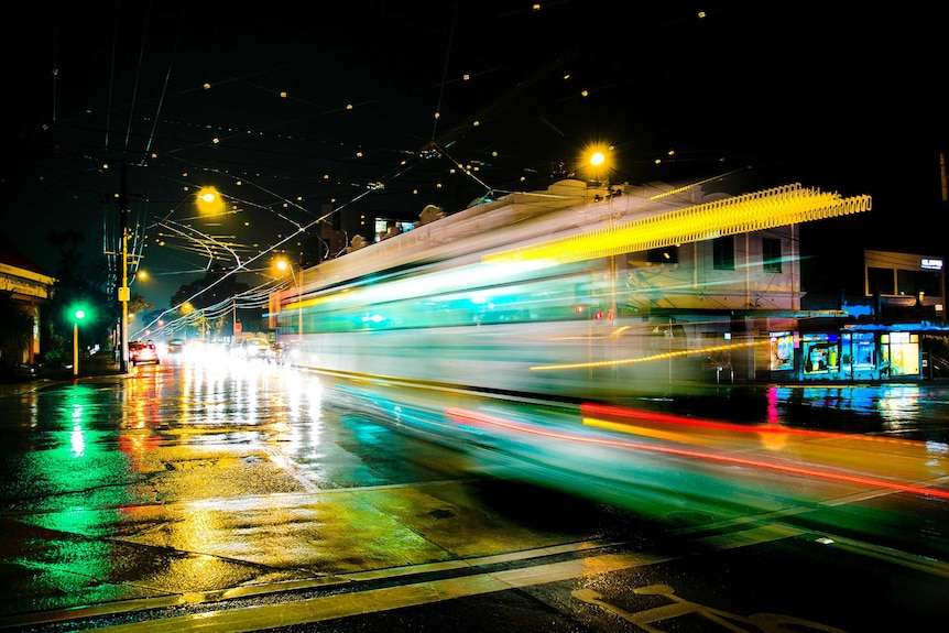 A tram moves through an intersection in Hawthorn on a rainy night.