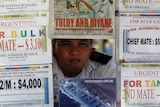 You view a man sitting behind a wall of flyers advertising shipping jobs in an outdoor booth in Manila.