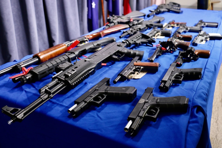A table of real guns and gel blasters demonstrates how difficult it is to tell the difference.
