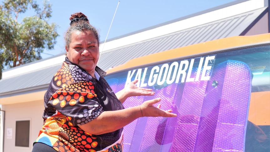 INdigenous woman with hair in bun stands next to laundry van