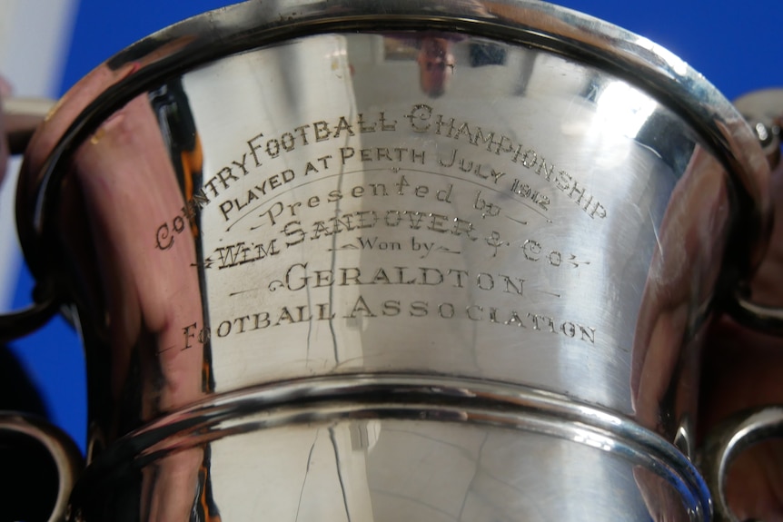 A silver trophy inscribed with words including Country Football Championship and Geraldton.