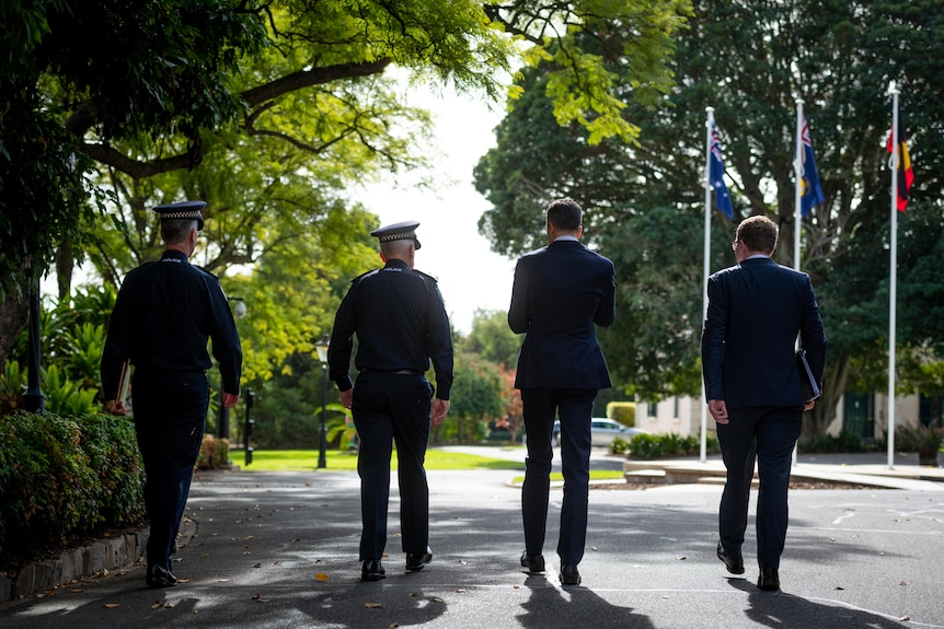 Four men walking in a row away with their backs to the camera