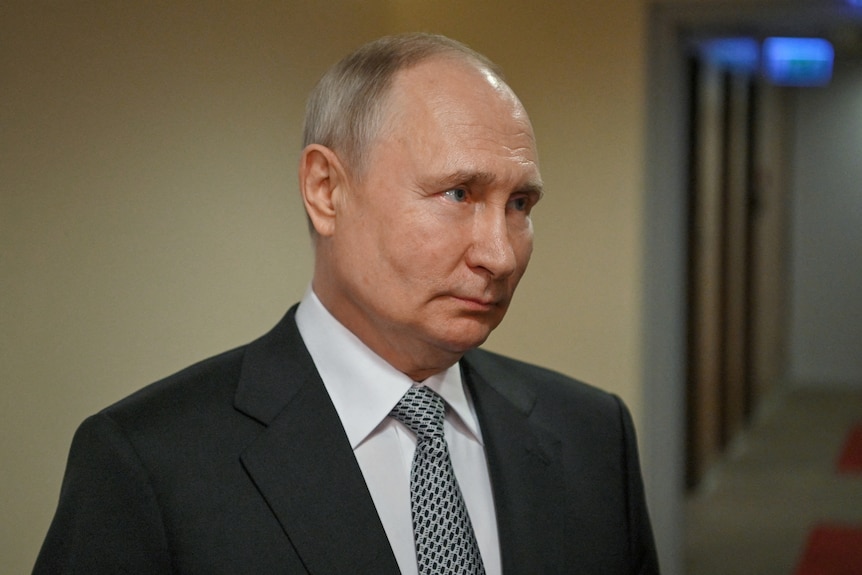 Vladimir Putin wearing a suit, looking off camera