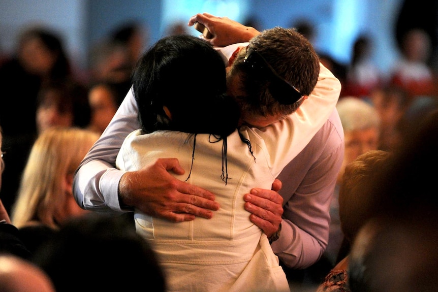 Mourners embrace each other during the service at the Quakers Hill Anglican Church.