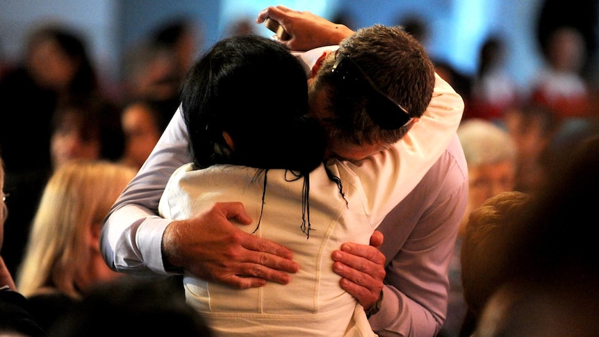 Mourners embrace during a memorial service for the victims of the Quakers Hill nursing home fire.