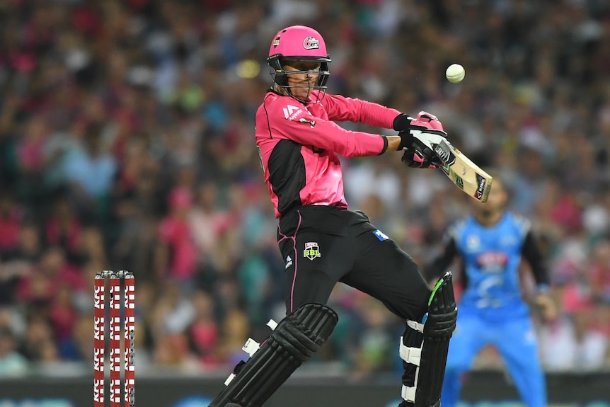 A cricket player named Johan Botha hits a shot while wearing a pink team uniform.