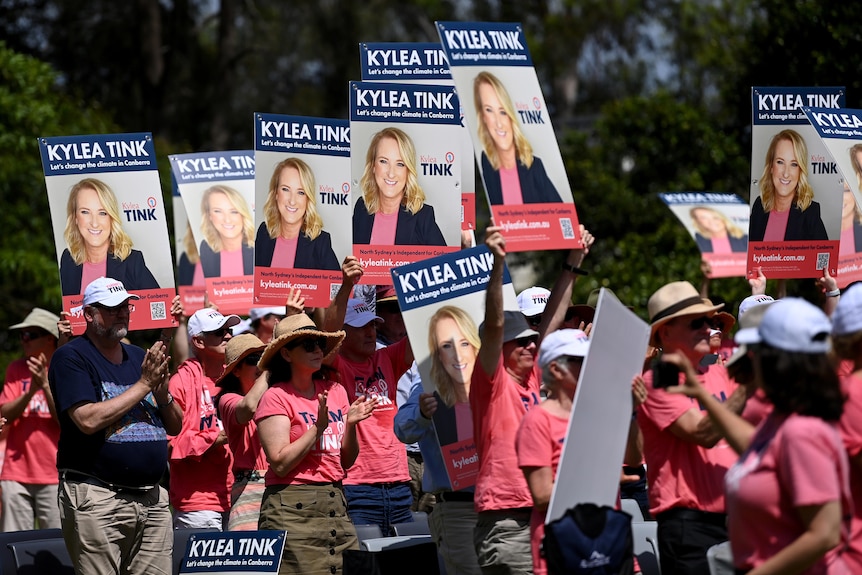 Un gruppo di sostenitori del candidato politico con in mano cartelli con la lettura di Kelia Tink