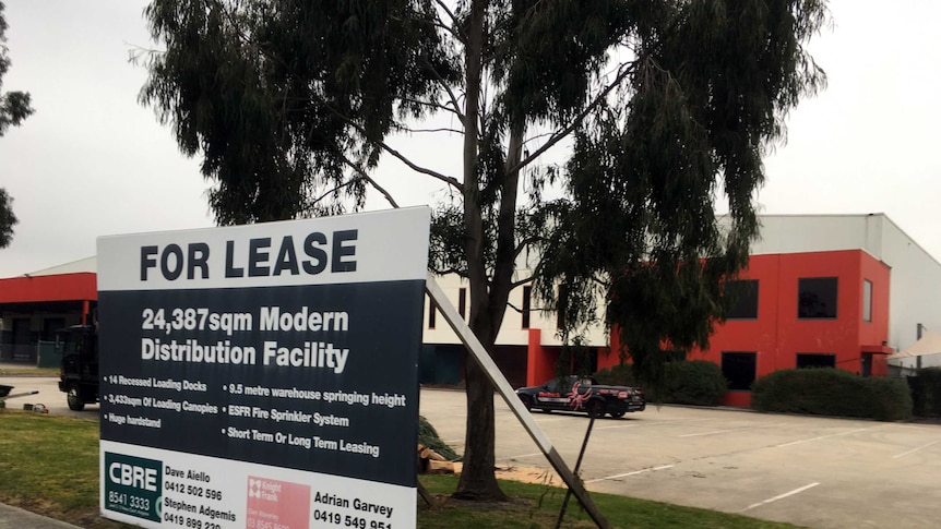 A warehouse with a 'for lease' sign out the front