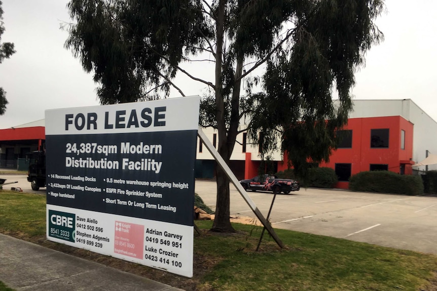 A warehouse with a 'for lease' sign out the front