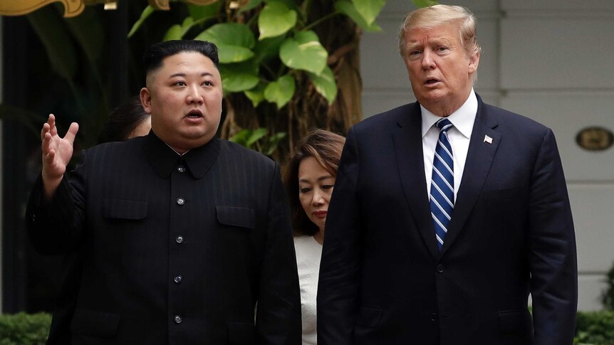 Kim Jong Un wears a black jacket and walks next to Donald Trump, who is wearing a dark suit