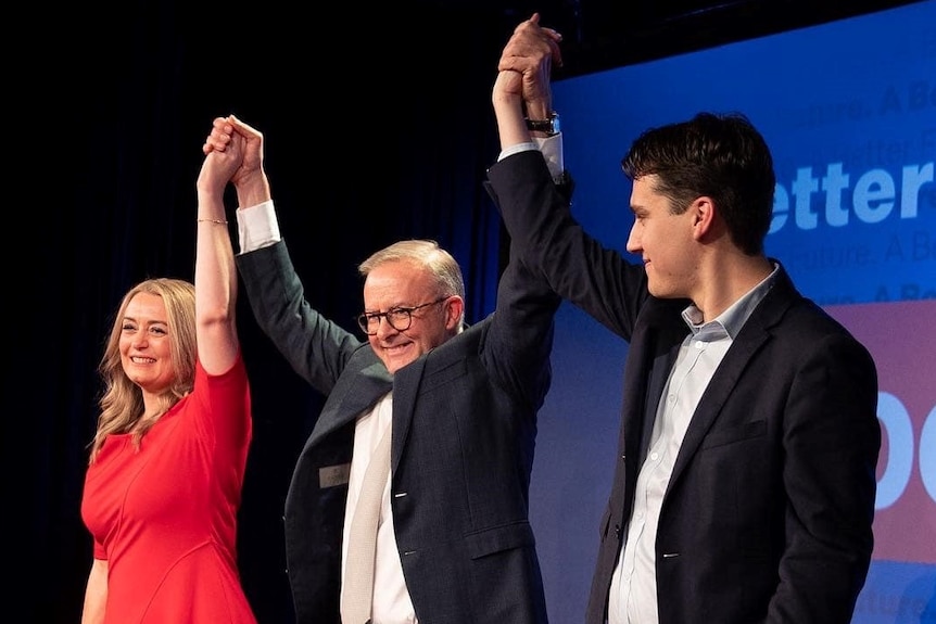 Anthony Albanese holds hands with a woman and a young man.