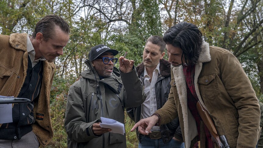 Colour photograph of Spike Lee directing actors outdoors amongst trees on the set of BlacKkKlansman.