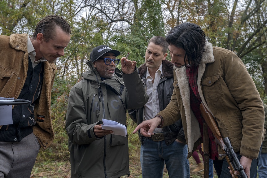 Colour photograph of Spike Lee directing actors outdoors amongst trees on the set of BlacKkKlansman.