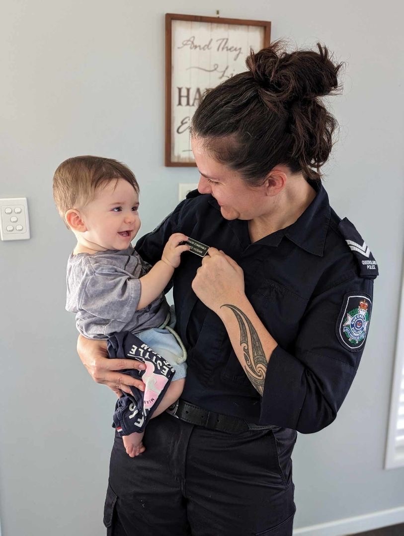 Renee Hogan in her police uniform holding her child. They are smiling at eachother. 