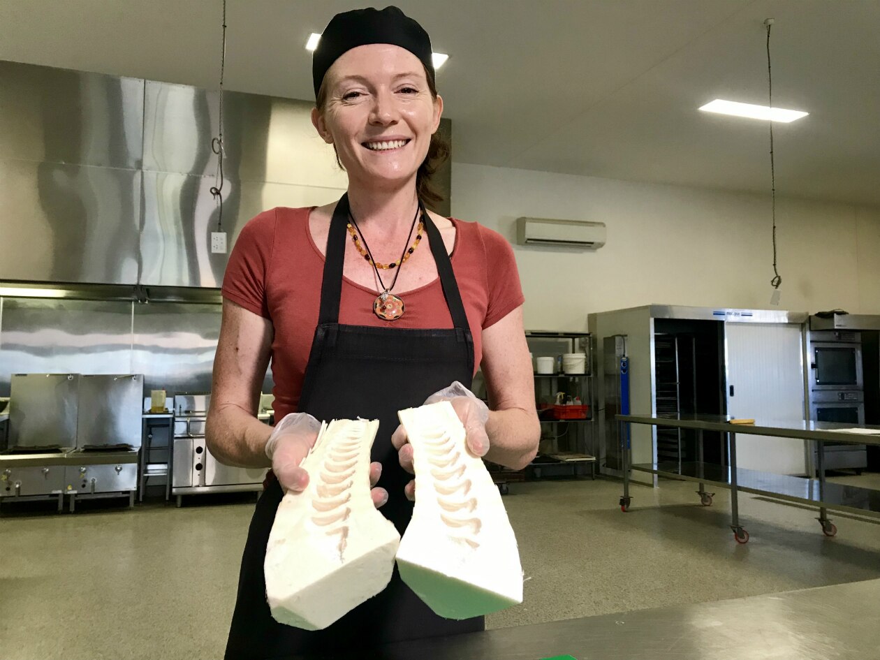 Becky Dart in a commercial kitchen showing a halved and husked piece of bamboo.
