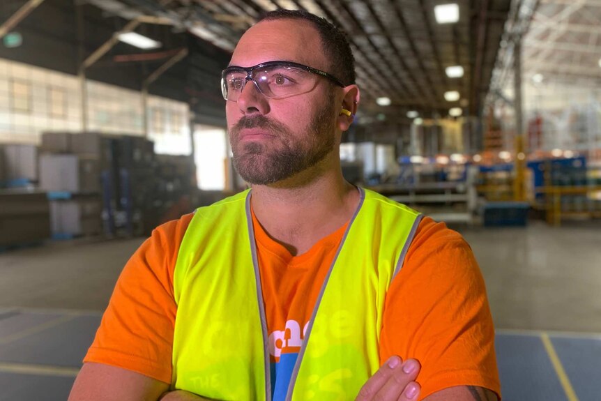 Ray Wynne stands in a factory wearing a high-visibility vest and eye protection.