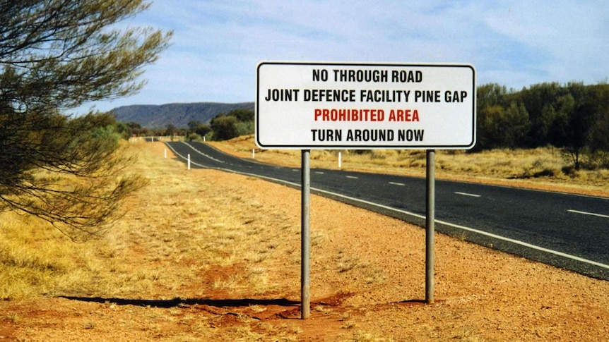 A sign beside a road reading - No Through Road, Joint Defence Facility Pine Gap, Prohibited Area, Turn Around Now.