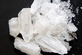Light-coloured crystals – the drug ice – on a dark table.
